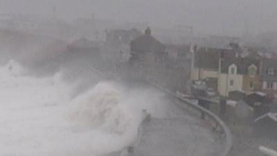 Waves crashing over the sea wall overlooking Chesil Cove, Portland, Dorset