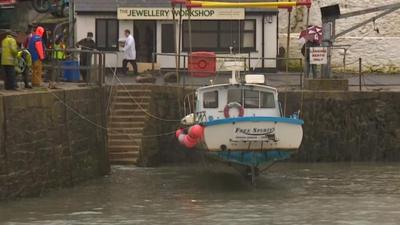 Boats are being removed from the harbour in Porthleven