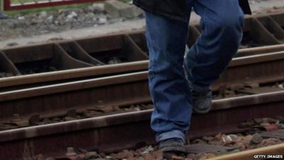 An immigrant crosses railway tracks in Calais, France