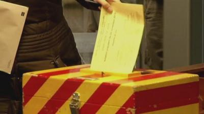 A Swiss voter puts her ballot in the ballot box