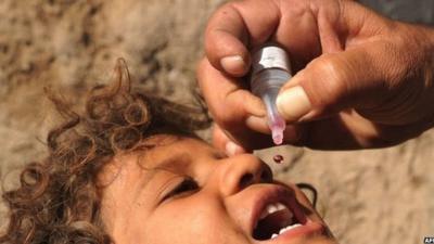 An Afghan health worker administers a polio vaccination to a child in Herat, Afghanistan, October 2013