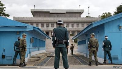 South Korean soldiers look towards the North Korean side as a North Korean solder approaches the UN truce village building that sits on the border of the Demilitarized Zone (DMZ) in Panmunjom, South Korea, on 30 September 2013