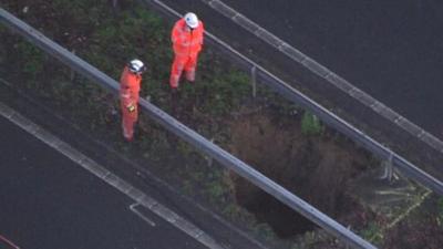 Men looking into a hole in the M2