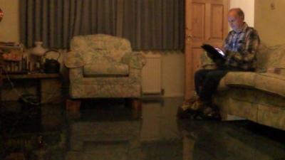 Man sits on sofa in flooded room