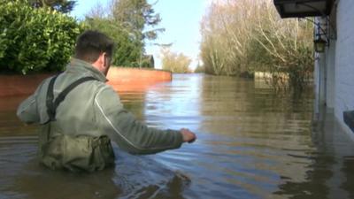 Man waist deep in water on flooded street