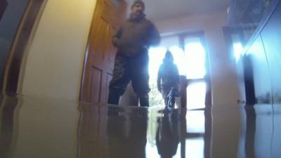 Men stand in flood water inside house