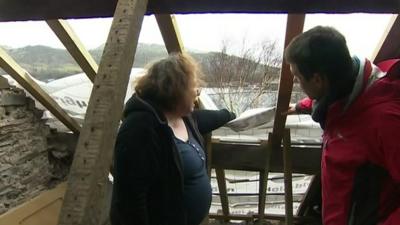 Lizzie Mowatt shows BBC reporter Hywel Griffith the damage to her house