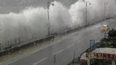 Police car being smothered by waves on Penzance promenade