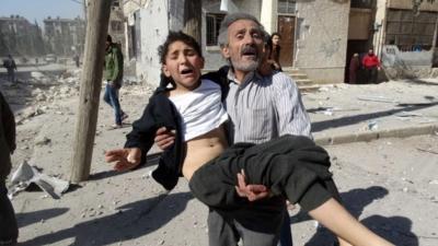 A man carries a wounded child after an air strike in Aleppo