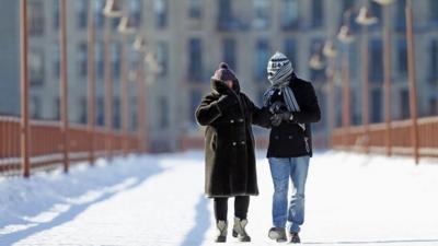 People walk along a bridge over the Mississippi River in Minneapolis