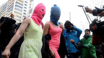 Wearing masks members of Russian punk group Pussy Riot, Nadezhda Tolokonnikova (C) and Maria Alyokhina (L)