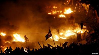 Anti-government protesters stand behind burning barricades in Kiev's Independence Square on 19 February 2014.