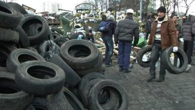 Protester carrying tyres to pile of tyres