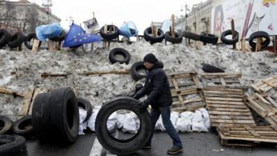 A man rolls a tyre at a barricade erected by Pro-European integration protestors in central Kiev