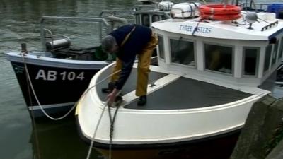 fisherman tying rope on boat