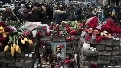 People walk by barrycades and makeshift memorials to the victims of the riots in central Kiev