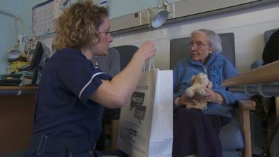 A nurse gives a food bag to an elderly patient