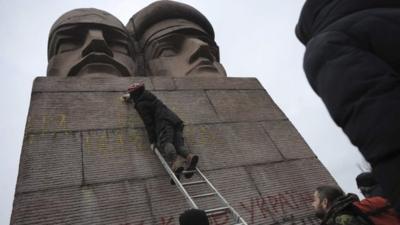 People paint on the KGB officers monument in Kiev, Ukraine