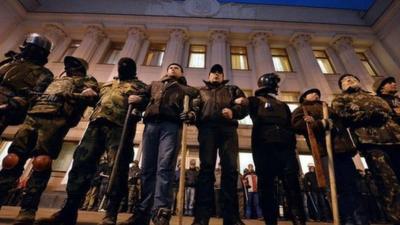 Maidan self-defence activists stand guard in front of the Ukrainian parliament during a session, in Kiev, on 24 February 2014.