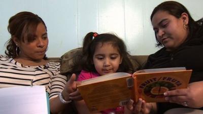 A mother and daughter get help with reading from a counsellor