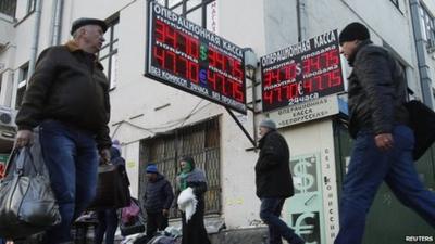 People walk past a currency exchange in Moscow