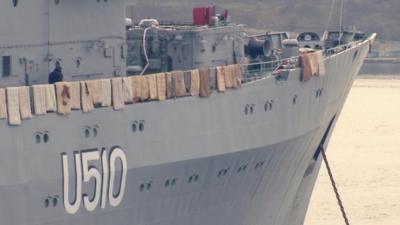 Mattresses draped over side of ship