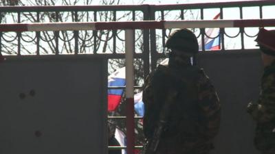 Soldiers inside the gates as Russian flags wave outside