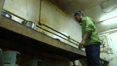 Migrant worker in unclean kitchen