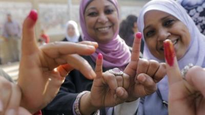 Egyptian women show their inked fingers after casting their votes at a polling station in Cairo