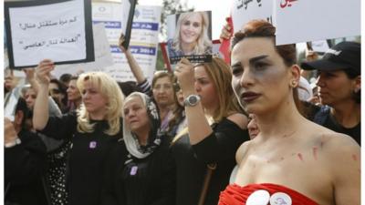 A woman with make-up made to look like a bruise walks with families of victims of domestic violence during a march against domestic violence, marking International Women's Day in Beirut