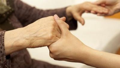Old person holding hands with carer