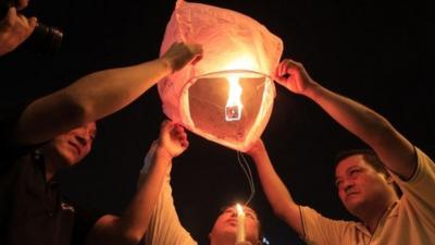 People prepare to release a sky lantern during a candlelight vigil for passengers