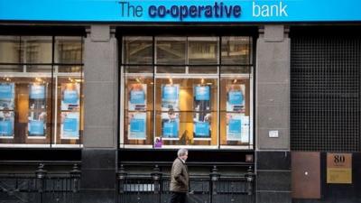 man walks past Co-op bank branch