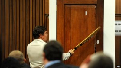 Police forensic expert Colonel Johannes Vermeulen demonstrating bat hitting door