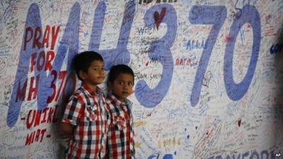 Two Malaysian children stand in front of messages board and well wishes to people involved with the missing Malaysia Airlines jetliner MH370