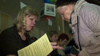 A voter at the polling station shows her passport