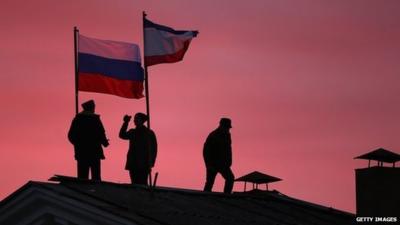 Cossack men install a Russian flag and a Crimean flag on the roof of the City Hall building on 17 March 2014 in Bakhchysarai, Ukraine.