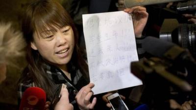 A relative of a Chinese passenger aboard the missing Malaysia Airlines Flight MH370 shows a paper reading "Hunger strike protest, Respect life, Return my relative, Don't become victim of politics, Tell the truth"