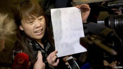 A relative of a Chinese passenger aboard the missing Malaysia Airlines Flight MH370 shows a paper reading "Hunger strike protest, Respect life, Return my relative, Don't want become victim of politics, Tell the truth"