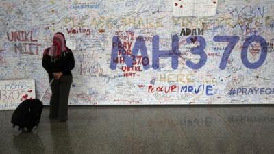 A woman reads messages for passengers aboard a missing Malaysia Airlines plane