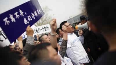 Grieving relatives of passengers on missing Malaysia Airlines flight MH370 protest with placards outside the Malaysian embassy in Beijing