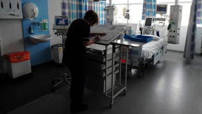 Nurse writes up notes in hospital ward