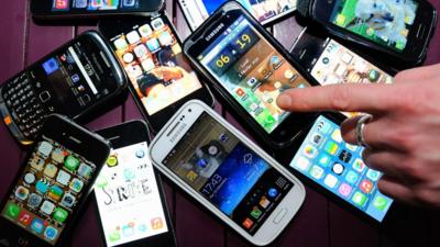 A finger points to a collection of smartphones