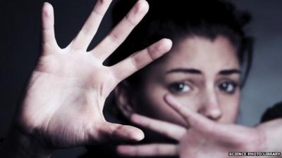 Frightened woman shielding her face with her hands