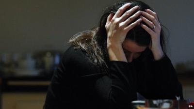 A woman holds her head in her hands