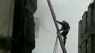 A fireman climbs a ladder outside the factory