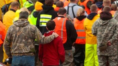 Workers and volunteers observe a moment of silence outside of the Oso Fire Department at 10:37 a.m. Saturday, March 29