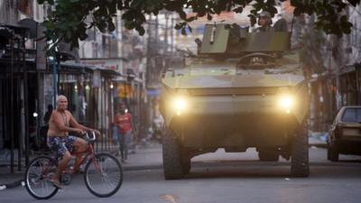 A man on a bicycle and a tank