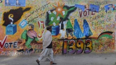 A man walks past an election themed mural in Kandahar, Afghanistan, 30 March 2014