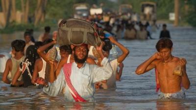 Villagers wade through flood waters in the village of Baseera near Muzaffargarh in Pakistan